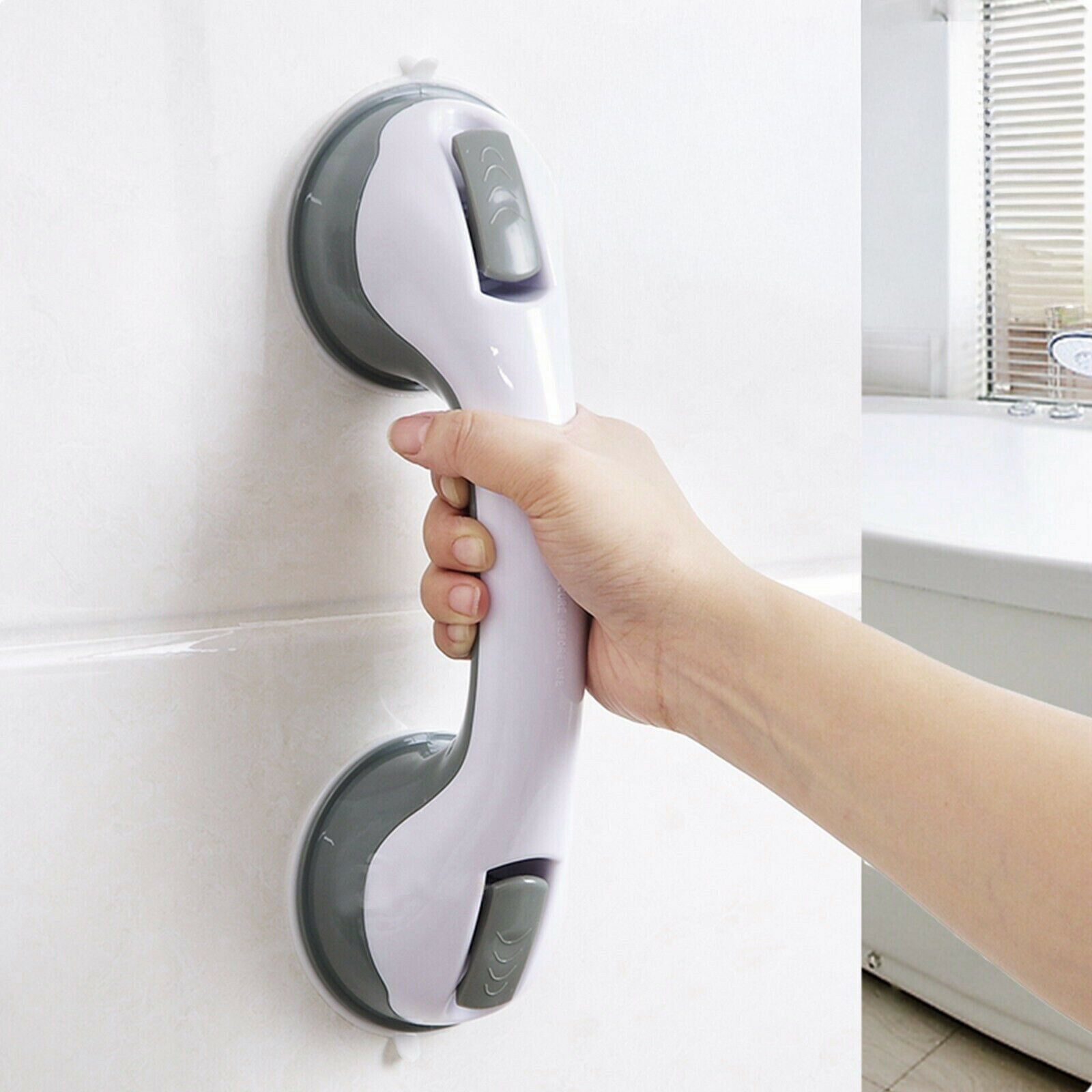 Hand holding a 16-inch suction grab bar mounted on smooth bathroom tile